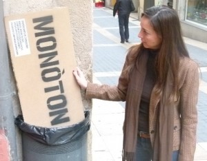 La regidora de comerç Patricia Anton llençant a la paperera un dels cartells amb una paraula de sentit negatiu