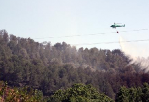 Un helicòpter aboca aigua sobre la zona afectada per l'incendi, aquest dissabte a la tarda