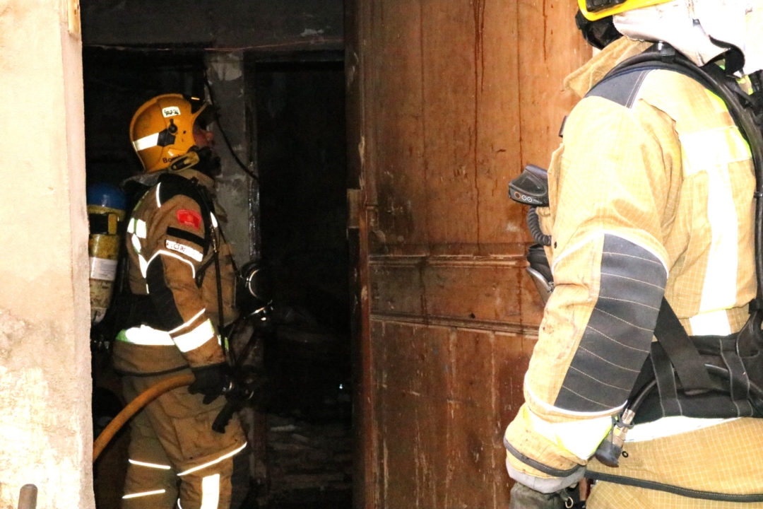 Un bomber inspeccionant l'afectació a l'interior de la casa, als baixos de l'immoble, al carrer dels Jueus. Foto: ACN