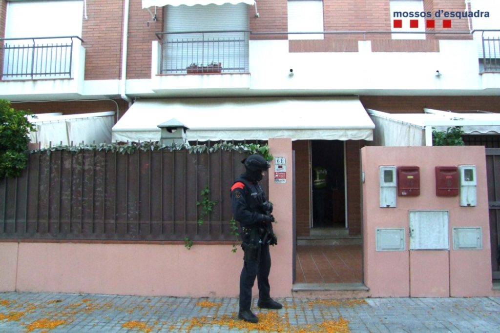 Un agent dels Mossos d'Esquadra vigila a les portes d'un dels domicilis escorcollats en l'operatiu policial per desarticular la banda criminal que cometia robatoris amb força. Foto: ACN