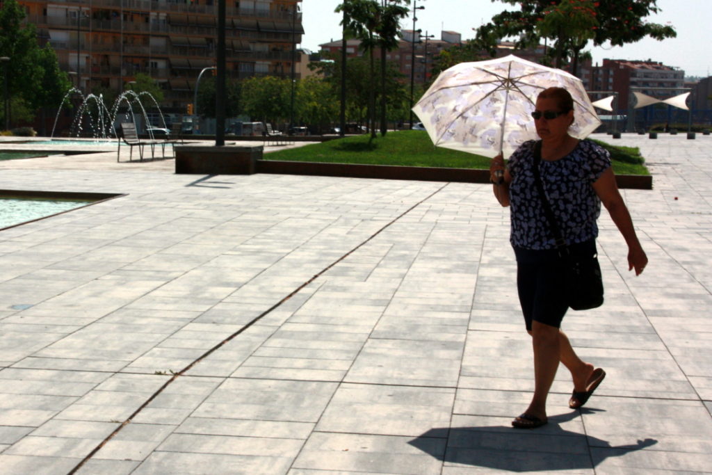 Una dona protegint-se del sol i la calor amb un paraigua. Foto: ACN
