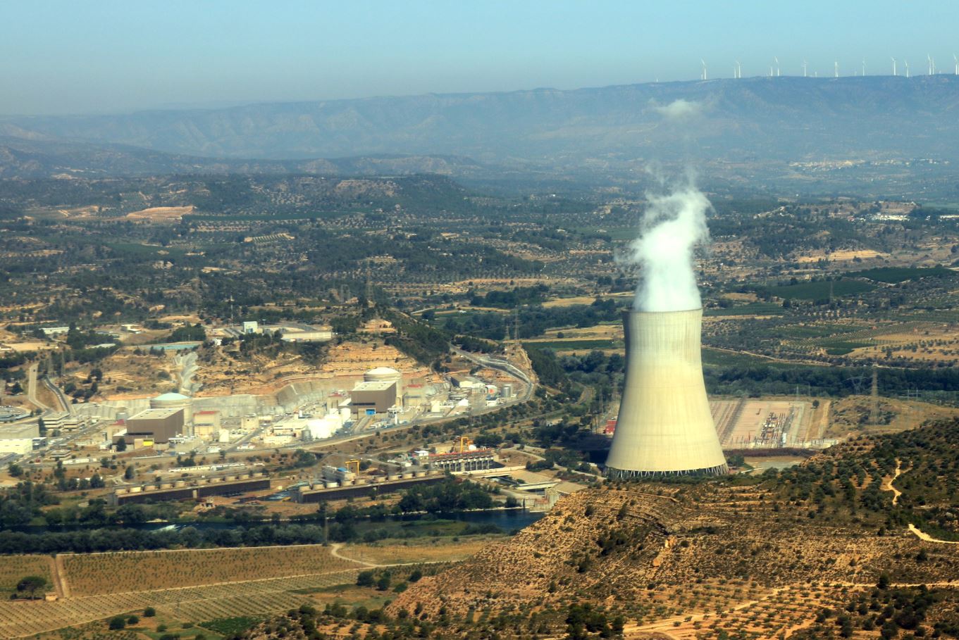 Vista aèria de la central nuclear d'Ascó, a la Ribera d'Ebre, amb la xemeneia fumejant a la dreta i els dos reactors a l'esquerra