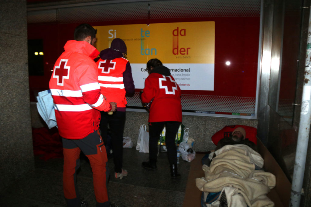 Voluntaris de Creu Roja oferint mantes i begudes als sensesostres. Foto: ACN