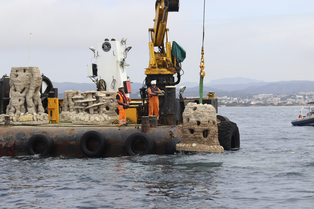 Dos operaris submergint un dels últims biòtops que vorejaran la primera muntanya