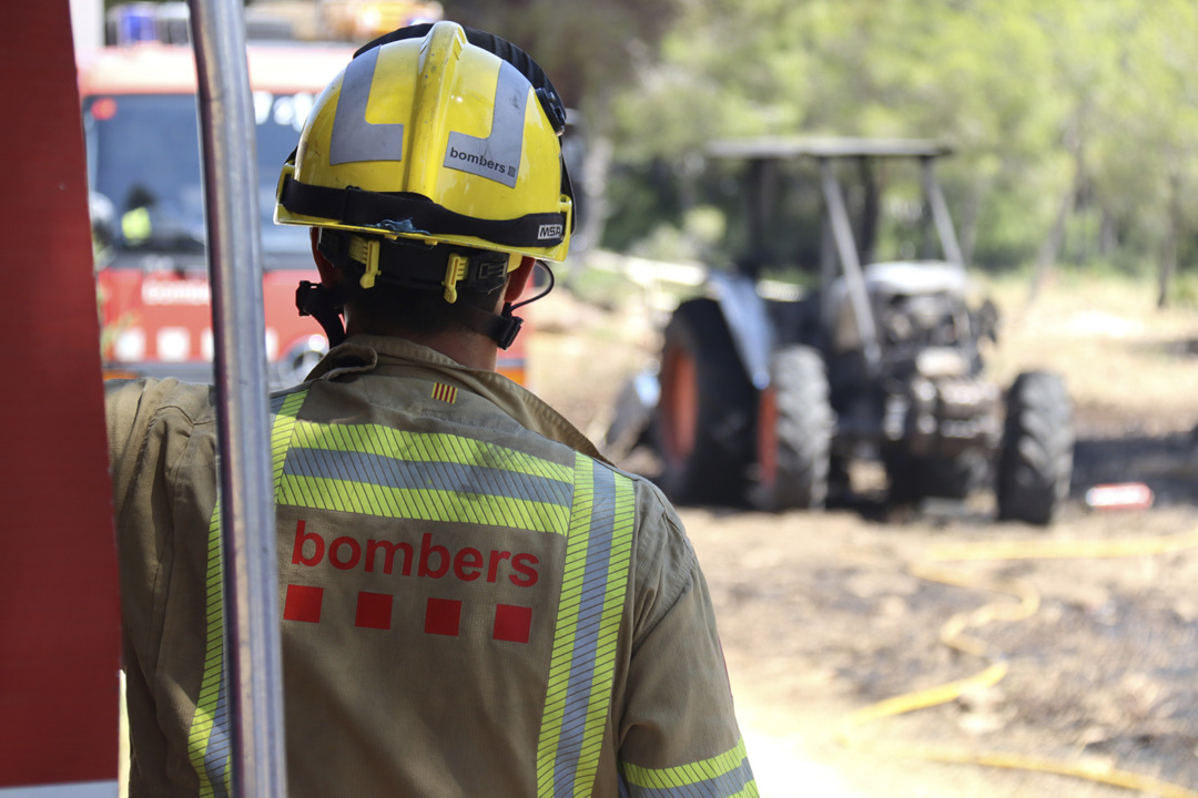 Un bomber mirant el tractor calcinat que va causar l'incendi. Foto: Neus Bertola